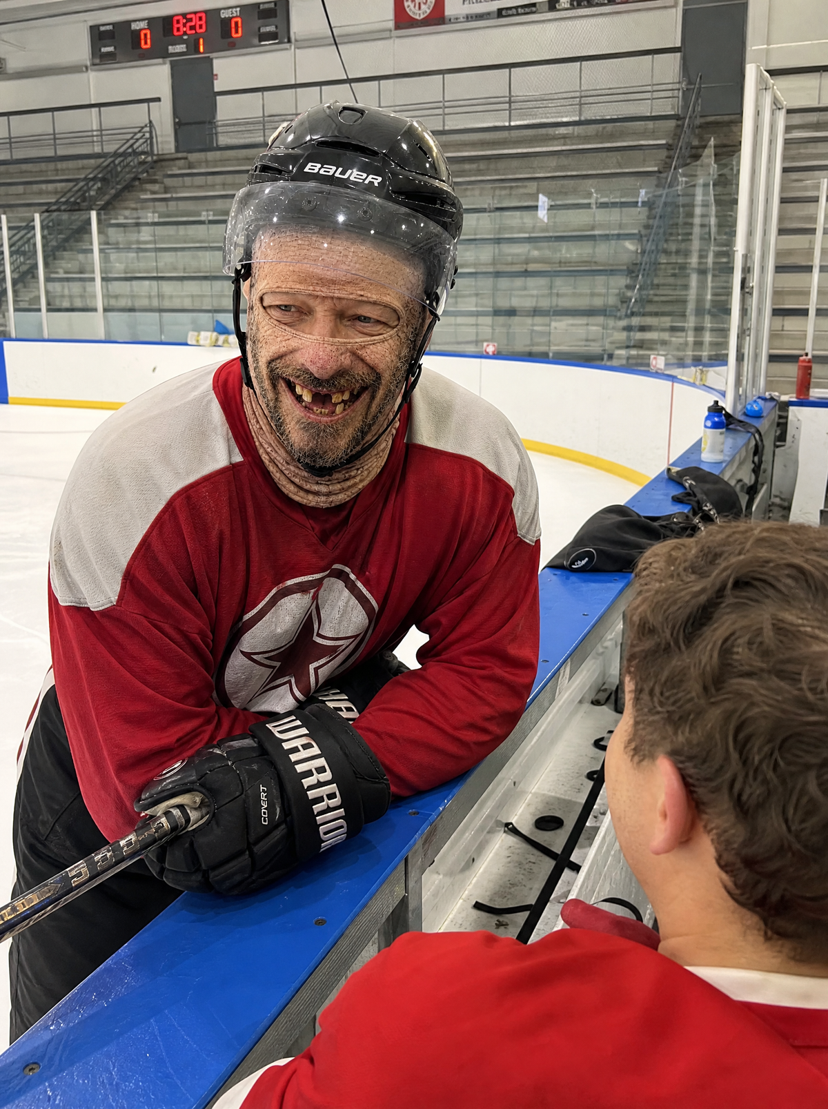 Hockey player leaning on the boards wearing a Frosty Face mask under his helmet